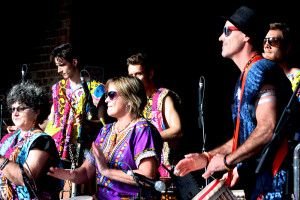 dancer in costume with djembe player behind